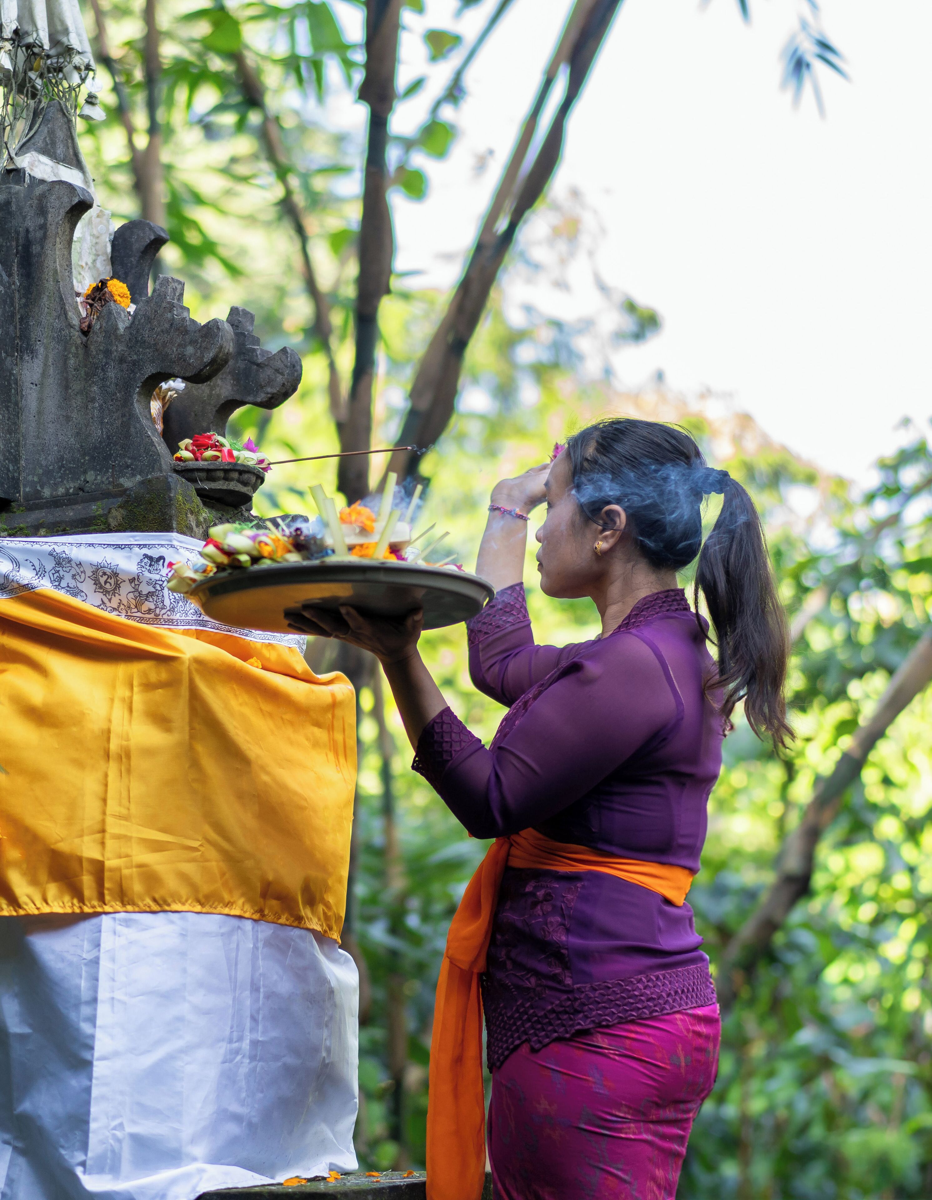 Une personne effectuant un rituel devant l’autel d’un temple, en déposant des offrandes.