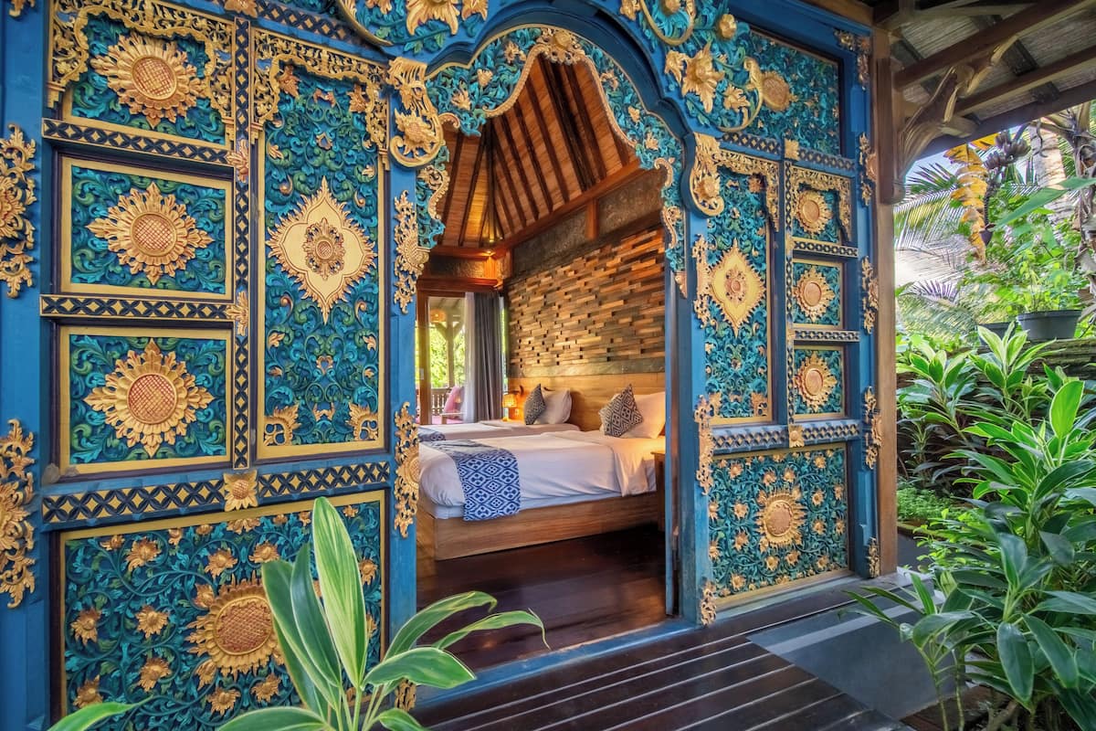 A room with a bed, wooden ceiling, and intricate blue and gold wall decorations.