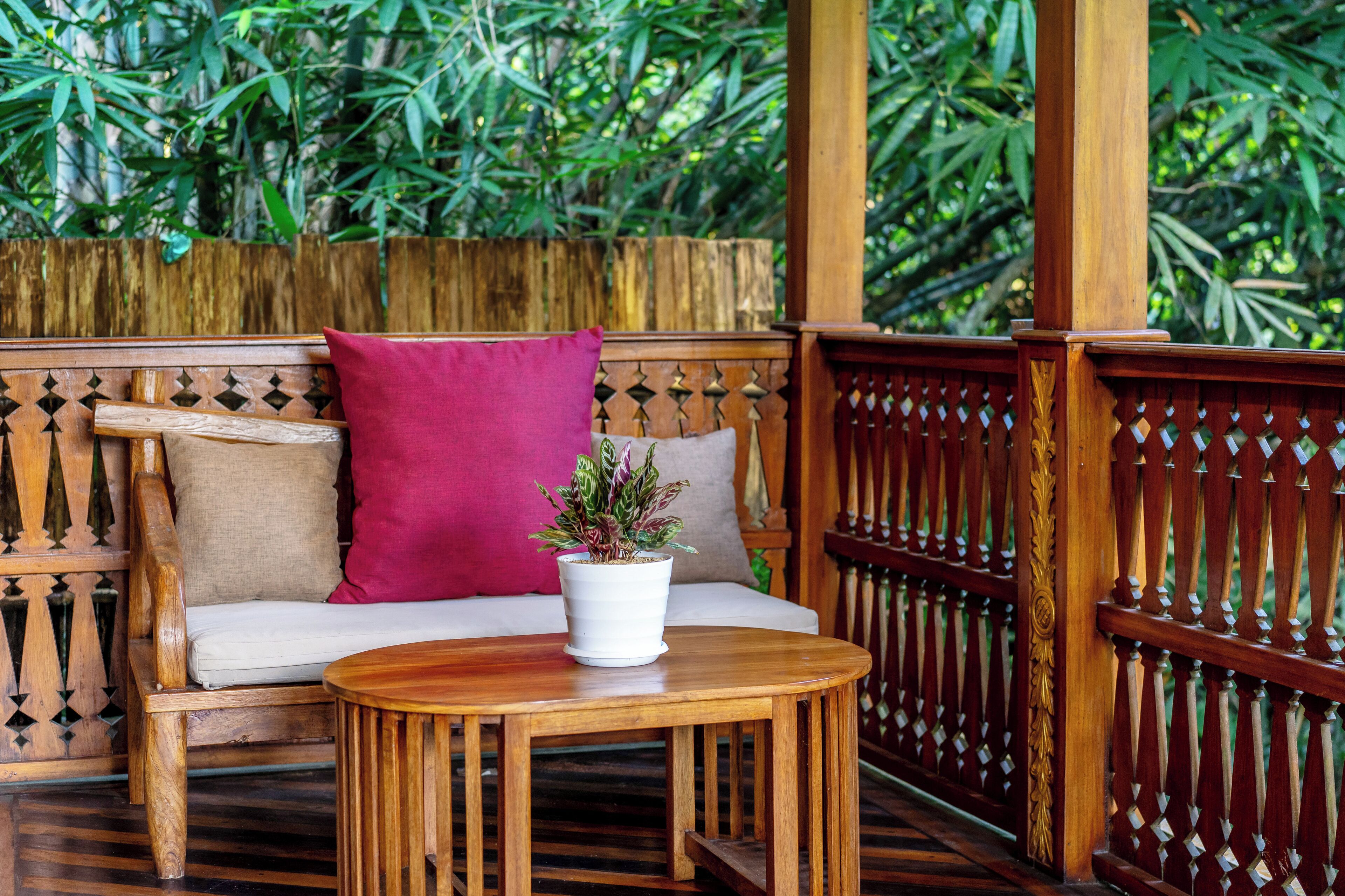 A wooden bench with cushions and a small table with a potted plant.