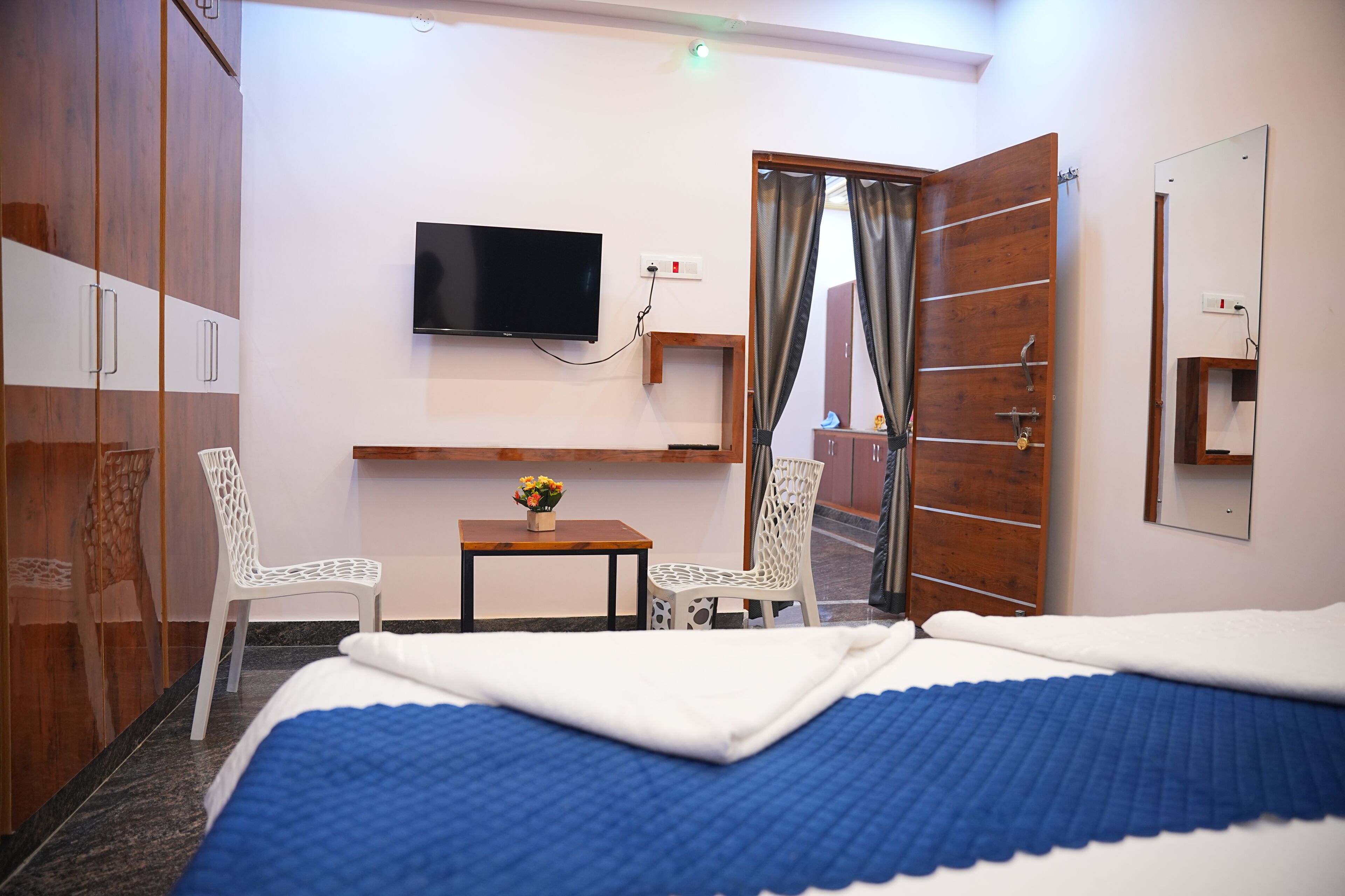A hotel room with a bed, a TV, a desk with a chair, and a wardrobe.