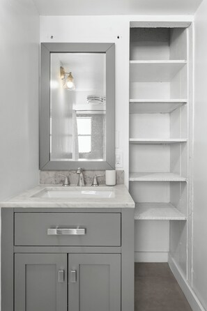A bathroom with a marble sink, a large mirror, and a built-in shelving unit. - Bay Harbor Sunset Two Bedrooms Apt (Bay Harbor Islands)