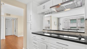 A modern kitchen with white cabinetry, a black countertop, and stainless steel appliances. - Bay Harbor Sunset Two Bedrooms Apt (Bay Harbor Islands)