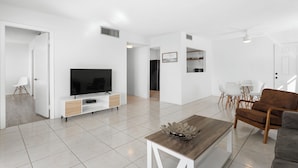 A modern living room with a flat-screen TV, wooden coffee table, and a brown sofa. - Bay Harbor Sunset Two Bedrooms Apt (Bay Harbor Islands)