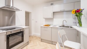 Una cocina moderna con horno empotrado, campana extractora de acero inoxidable y encimera blanca.