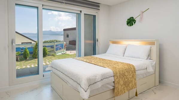 Un dormitorio con cama, vistas a una piscina y montañas, y un ventanal grande.