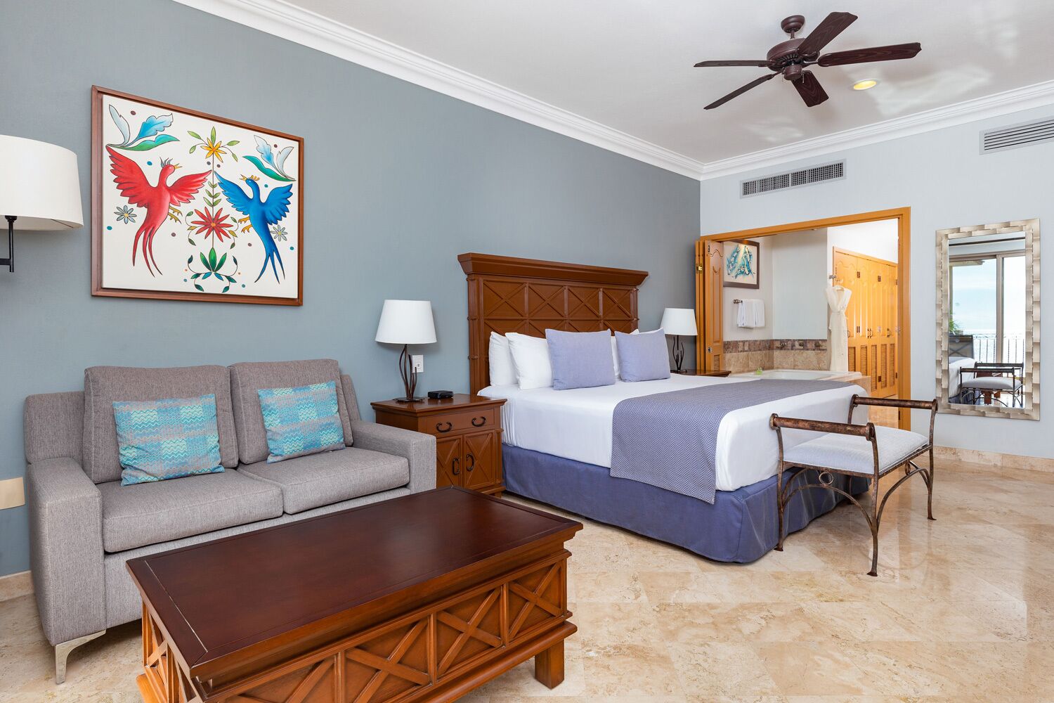 Une chambre d’hôtel avec un lit, un canapé, une table basse et un ventilateur de plafond.