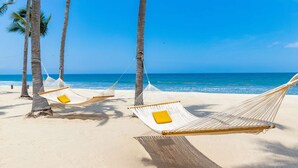 A beach with hammocks tied to palm trees, a clear blue sky, and the ocean in the background. - Luxury 3BR Villa for Christmas Week – Relax & Unwind in Nayarit! (Nuevo Nayarit)