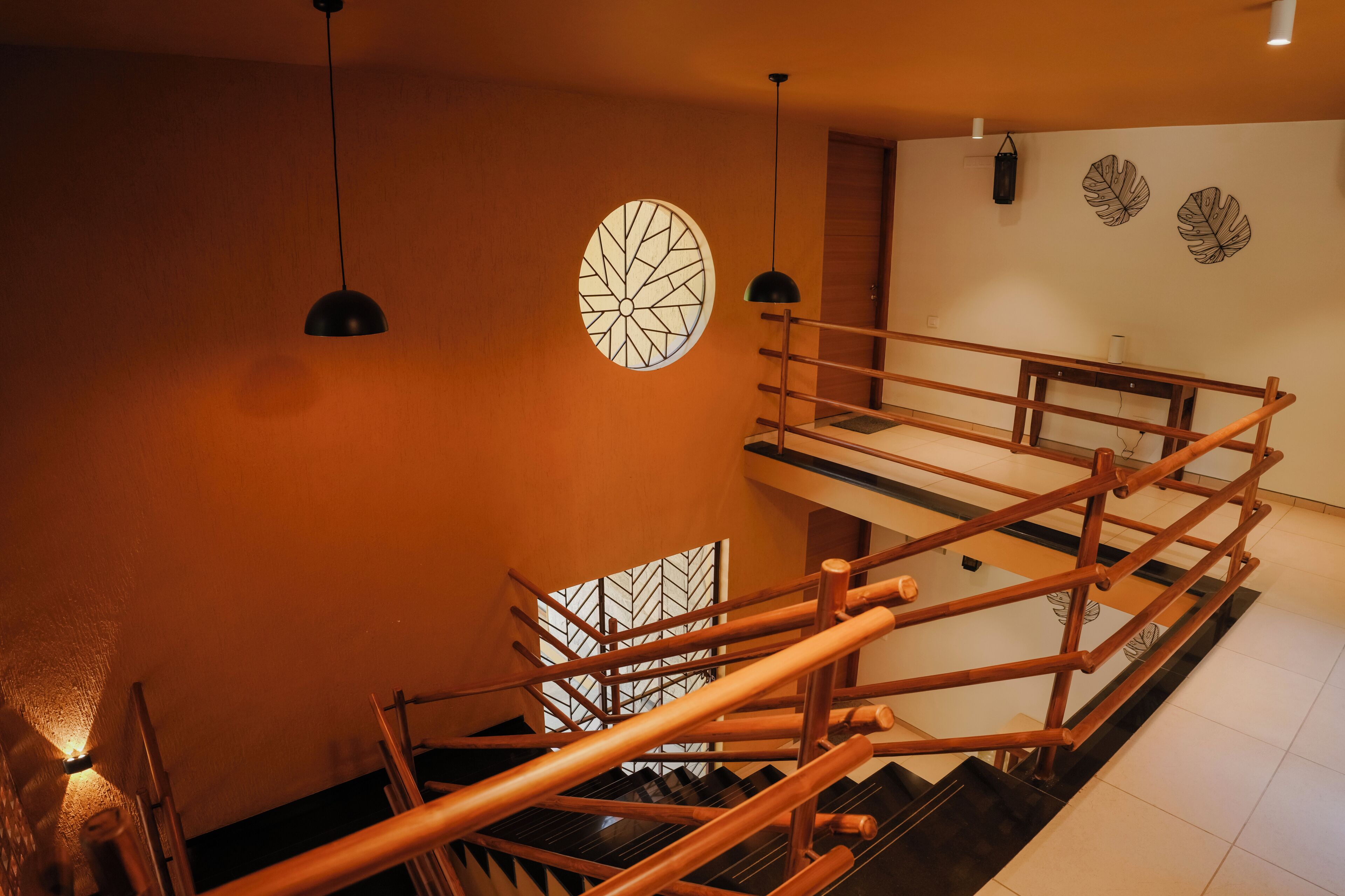 A multi-level wooden staircase with a handrail, a circular wall decoration, and a hanging pendant light.
