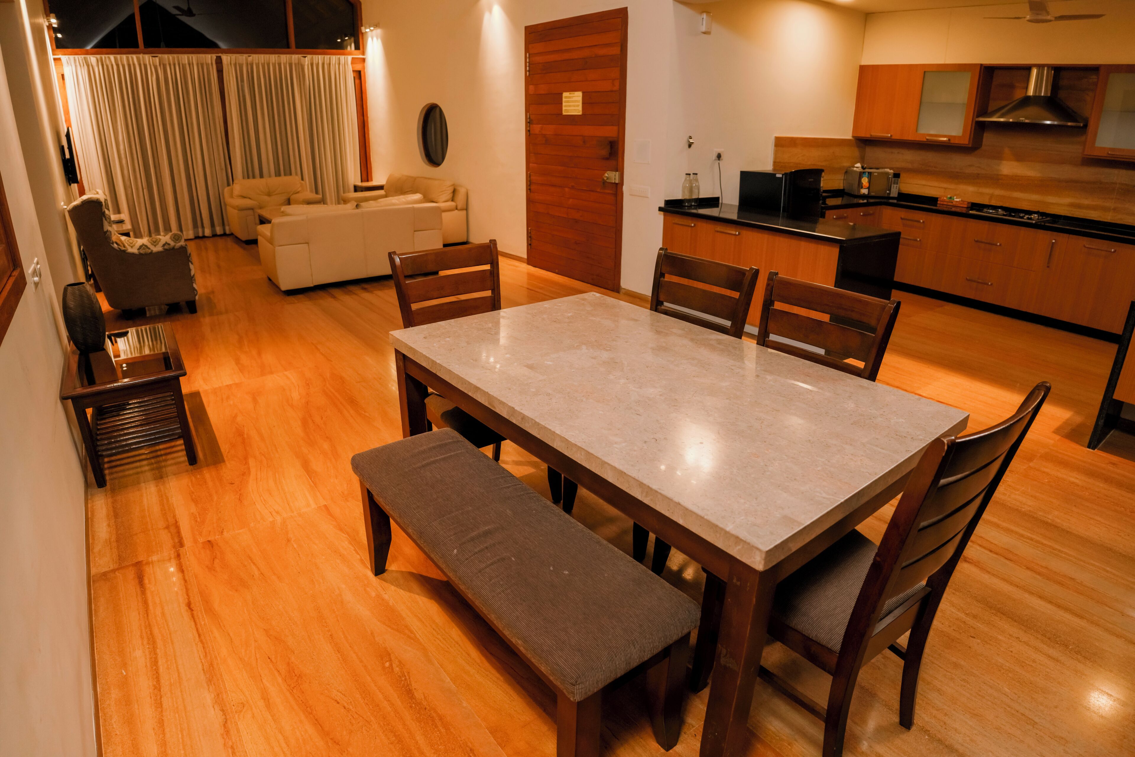 A dining area with a marble table, wooden chairs, and a bench.