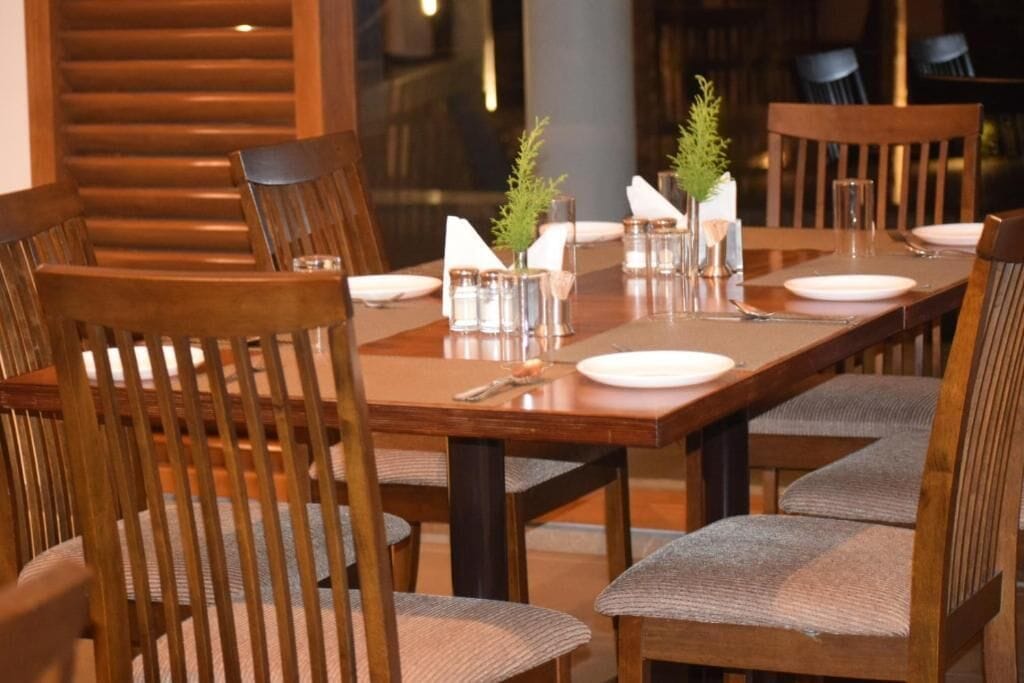 A dining table set with chairs, salt and pepper shakers, and a small plant.