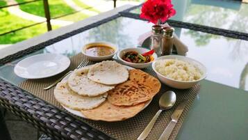 A table set with flatbreads, rice, curry, and a flower.