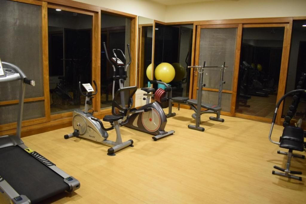 Un gimnasio con equipamiento de ejercicio, incluyendo cintas de correr, bicicletas estáticas y máquinas de pesas.