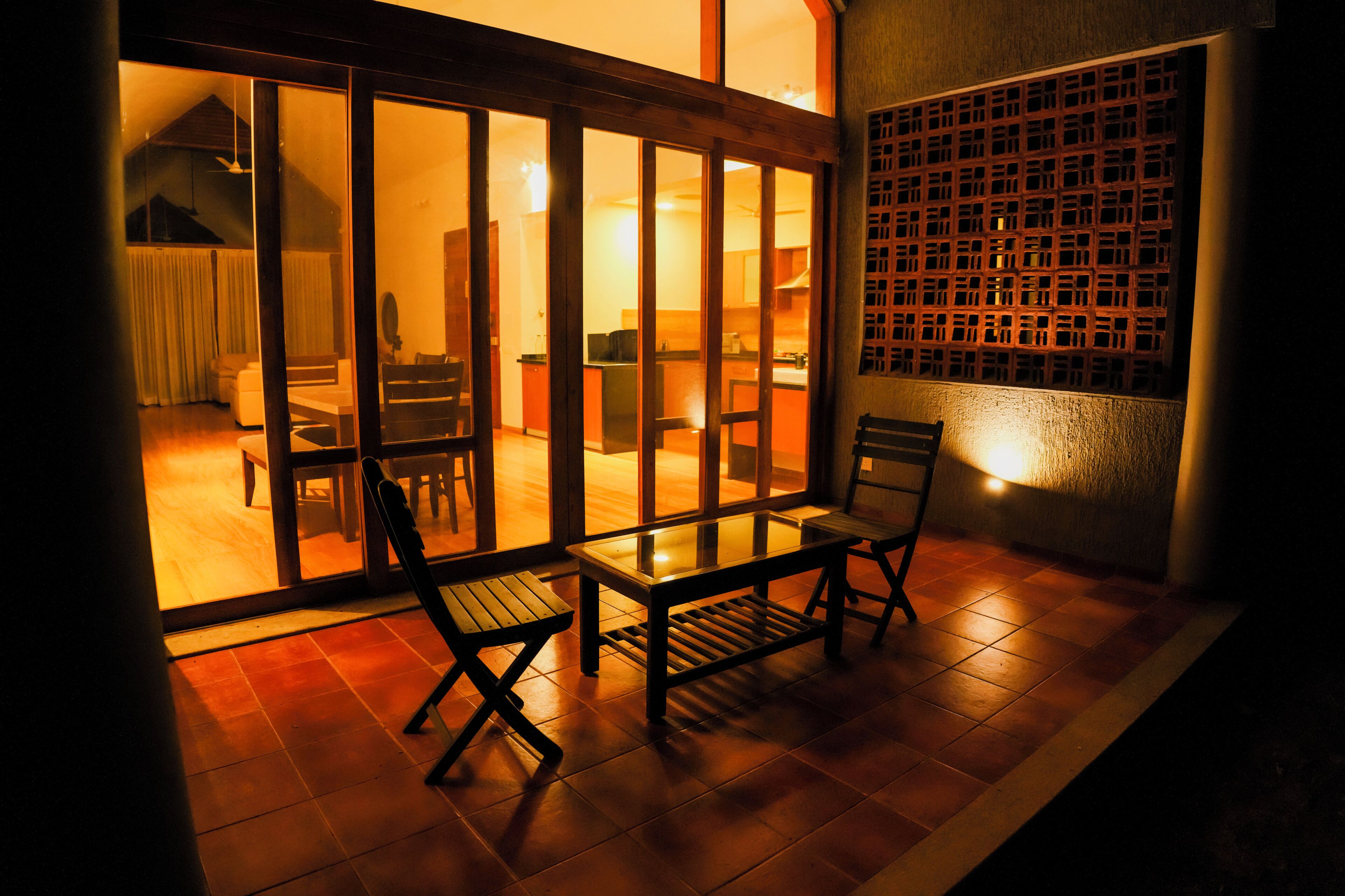 A room with a sliding glass door leading to a dining area, a small table with chairs, and a decorative wall panel.
