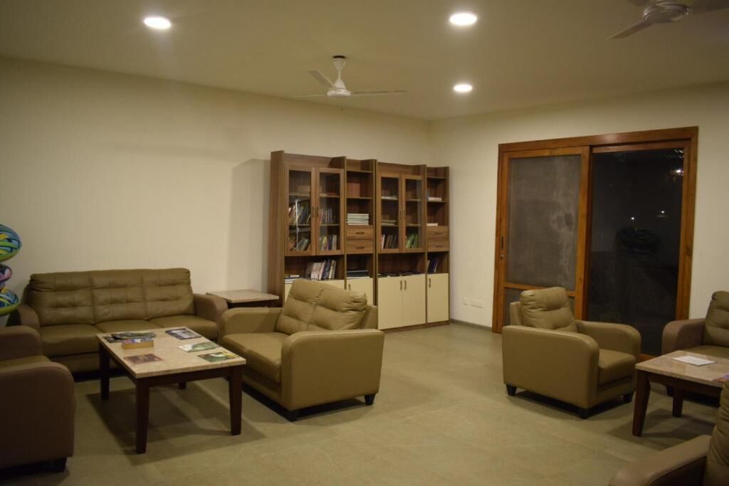 Una sala de estar con un sofá, sillones, una mesa de centro y una estantería.