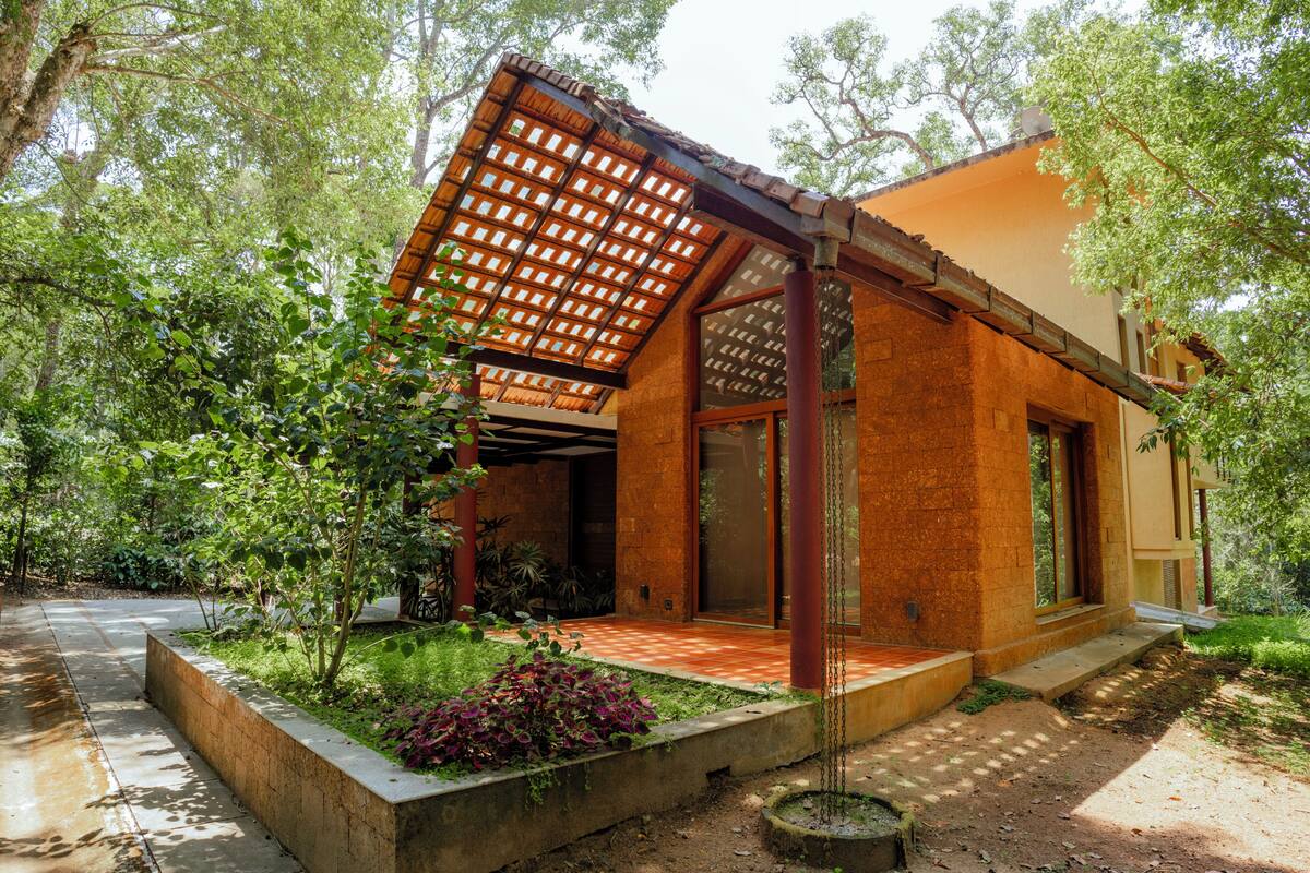 Une maison moderne dotée d’un porche abrité, de grandes fenêtres et d’un jardin.