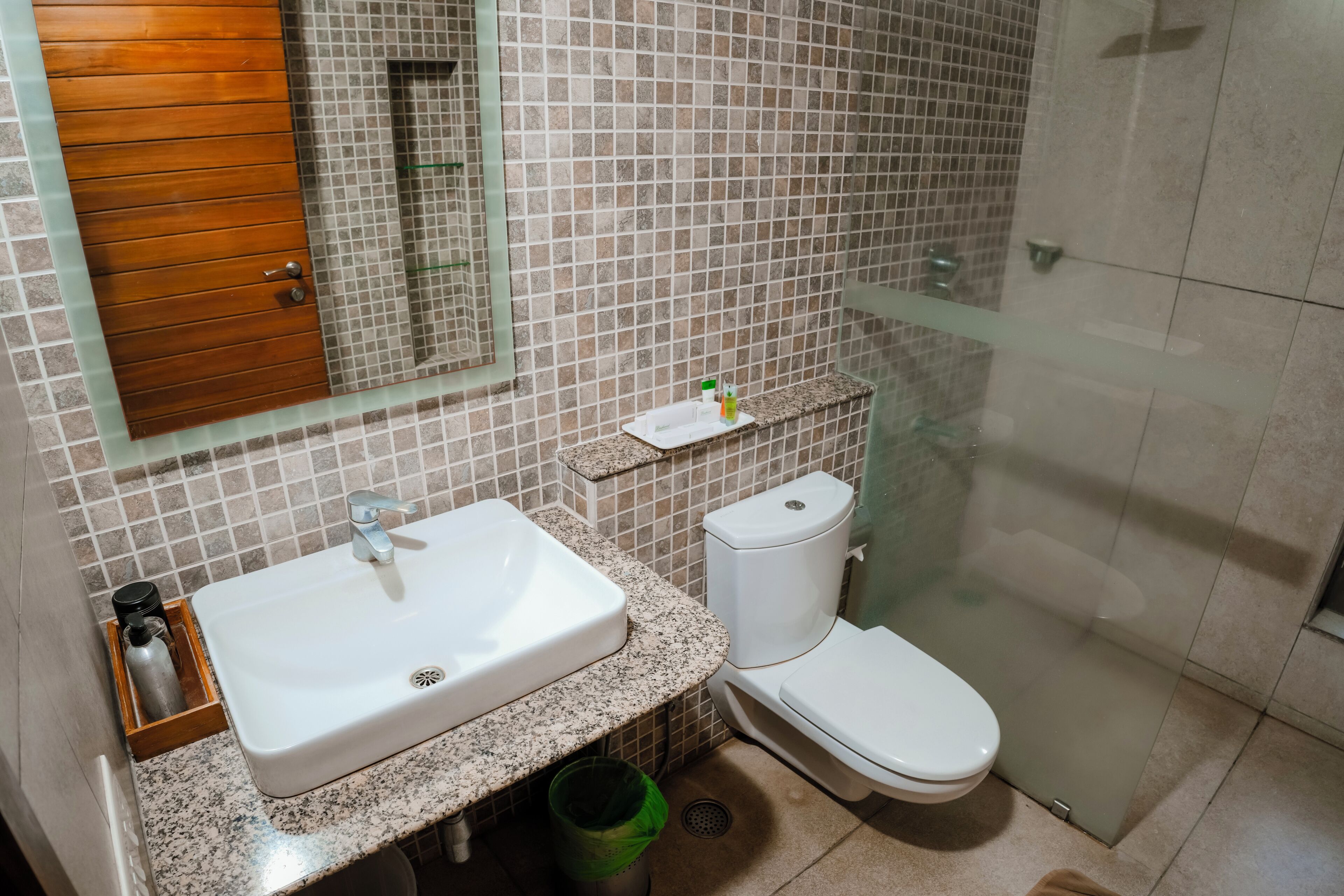 Et badeværelse med en hvid vask, toilet og en brusekabine i glas.