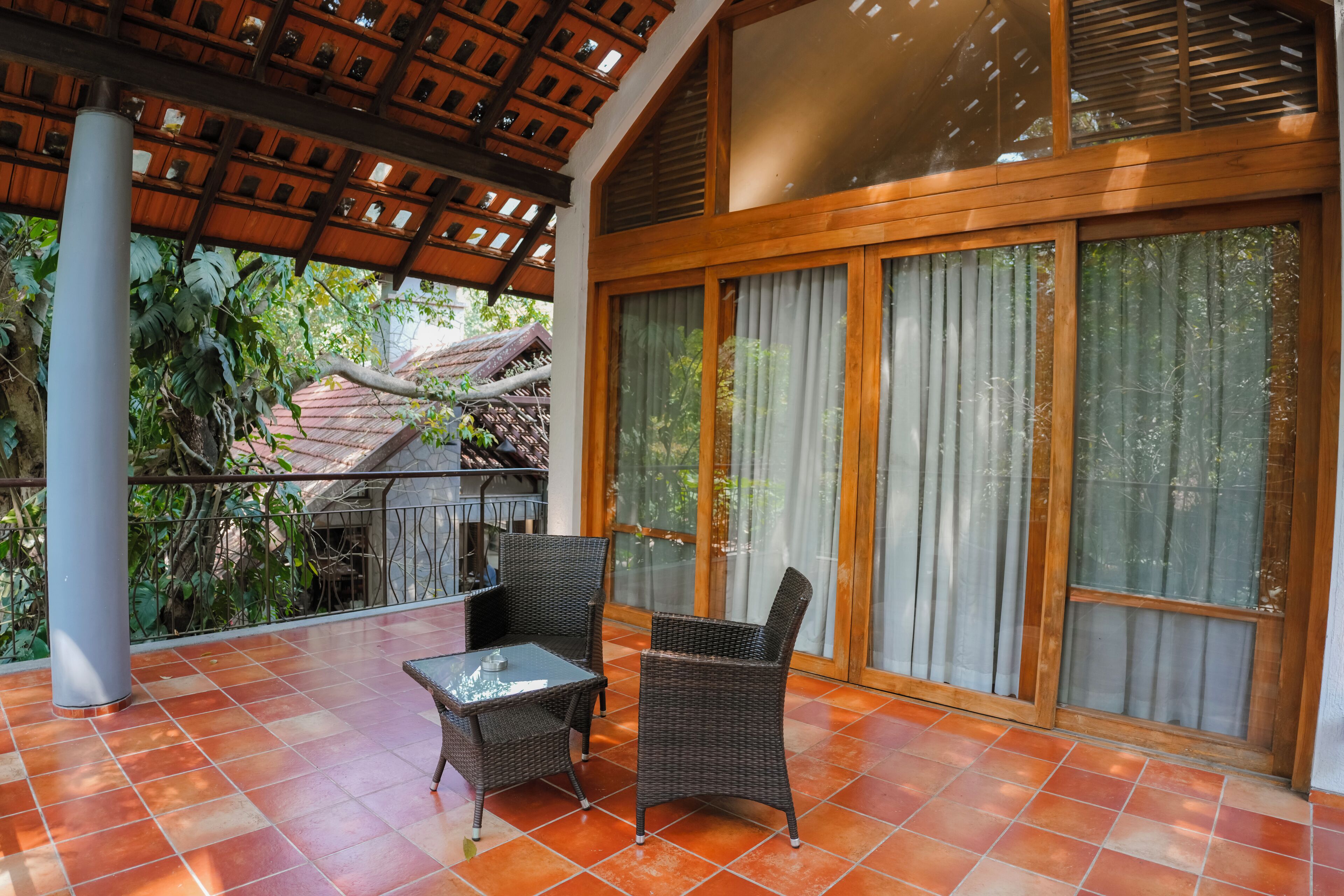 A covered patio area with wicker furniture and large windows.