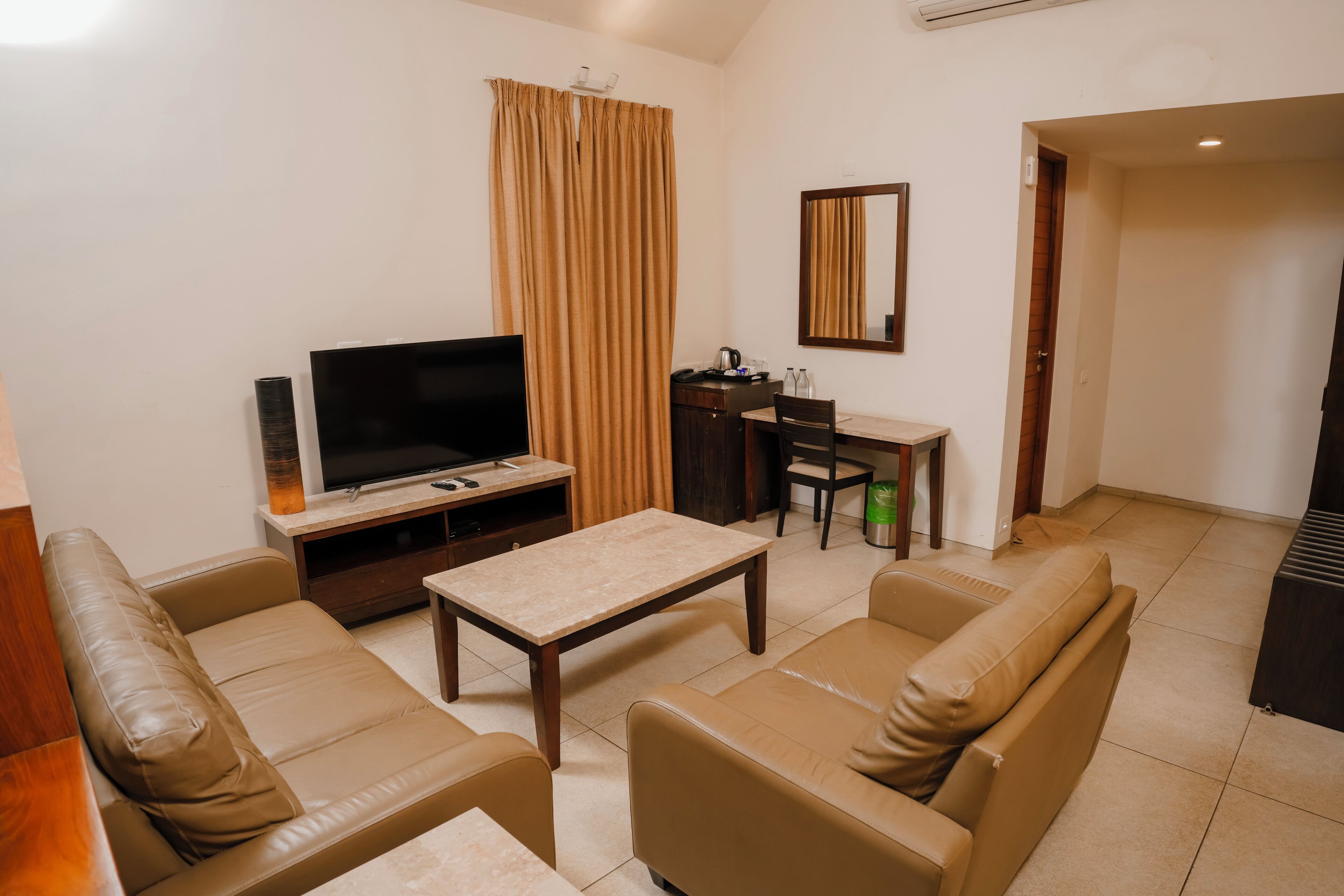 Una sala de estar con televisor, sofá, mesa de centro y cortinas.