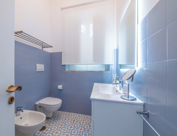 Un baño con inodoro, lavamanos y espejo.