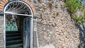 A stone wall with a metal gate and steps leading to a building. - Villa Pelagium on the Amalfi Coast (Praiano)