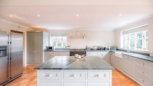 A modern kitchen with white cabinets, a granite countertop, a built-in oven, and a large window providing natural light.