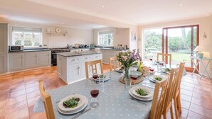 A spacious kitchen with a central island, large windows, and a dining area set for a meal.