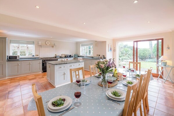 A spacious kitchen with a central island, large windows, and a dining area set for a meal.