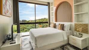 A modern bedroom with a large bed, a TV, and a view of greenery.