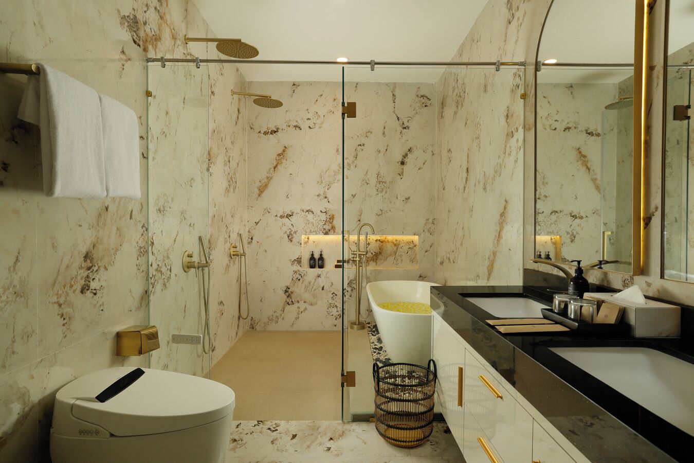 A modern bathroom with a glass-enclosed shower, a white bathtub, and a vanity with a black countertop.