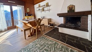 A cozy dining area with wooden furniture, a fireplace, and a view of the mountains. - Yéti 3 - T3 + Mezzanine (CHATEL)