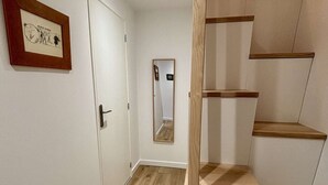 A hallway with a wooden staircase, a door, and a framed picture on the wall. - Yéti 3 - T3 + Mezzanine (CHATEL)