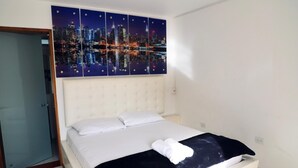A hotel room with a large bed, a cityscape artwork above the bed, and a white headboard. - Mountain View (Girardota)