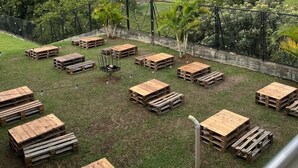 A view of a mountainous landscape with a rainbow, wooden pallets arranged in a pattern, and a grassy area with trees. - Mountain View (Girardota)