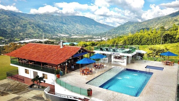 A hotel with a swimming pool, outdoor seating, and a view of mountains. - Mountain View (Girardota)