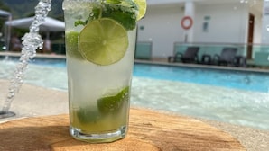 A glass of a lime-based drink with mint, placed on a wooden surface near a pool. - Mountain View (Girardota)