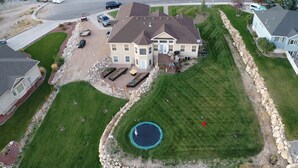 A large house with a swimming pool, surrounded by well-maintained lawns and a stone border.