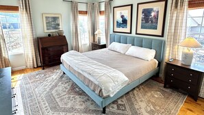 A bedroom with a bed, a nightstand, a dresser, a ceiling fan, and two framed pictures on the wall.