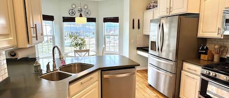 A modern kitchen with a dishwasher, refrigerator, stove, and wooden flooring.