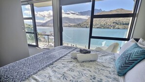 Une chambre avec un grand lit, donnant sur un lac, et avec des montagnes en arrière-plan.