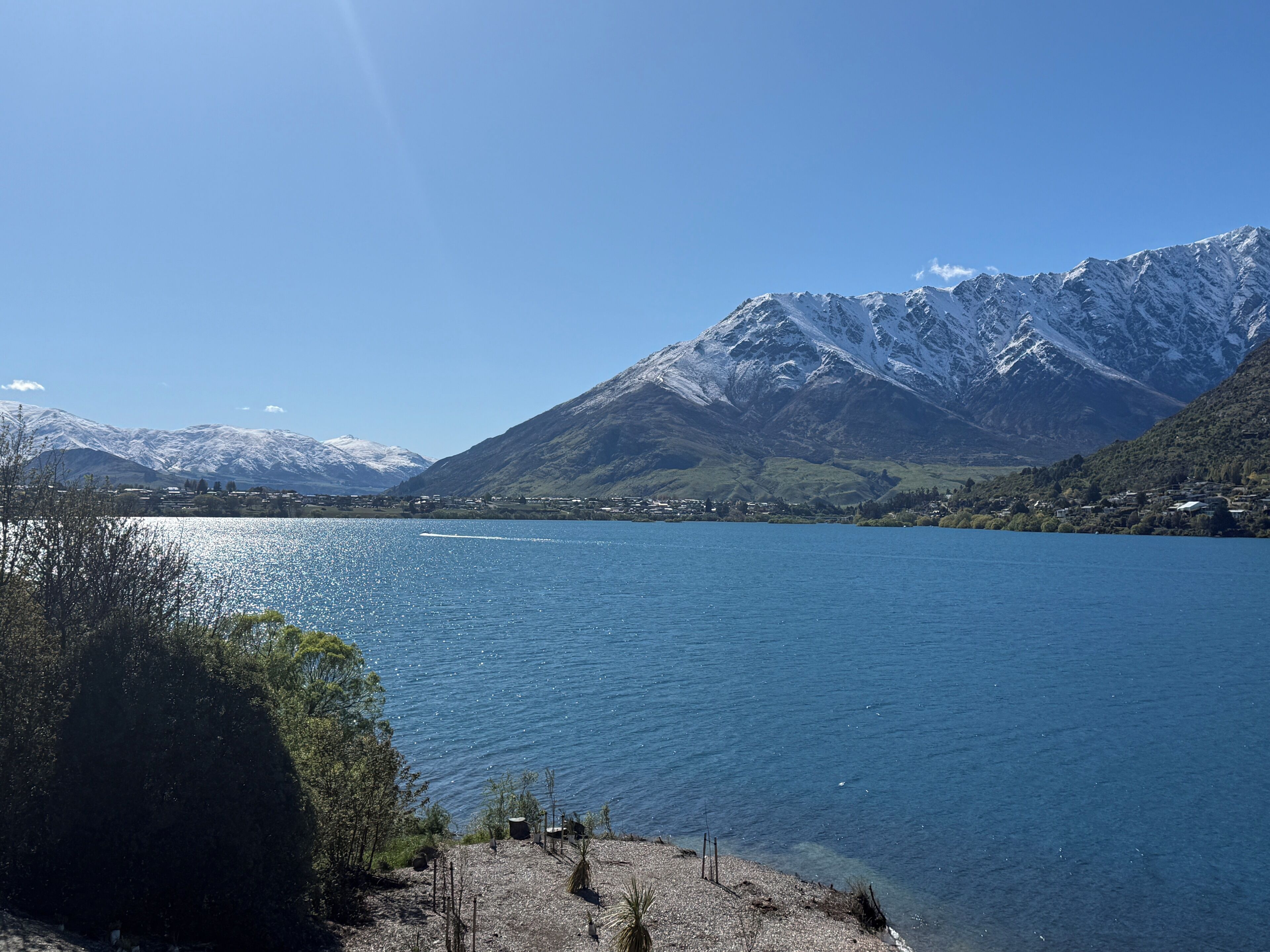 A lake with mountains in the background and a small settlement across the water.
