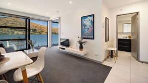 Un salon moderne doté d’une grande fenêtre offrant une vue panoramique, d’un téléviseur fixé au mur et d’un design minimaliste.