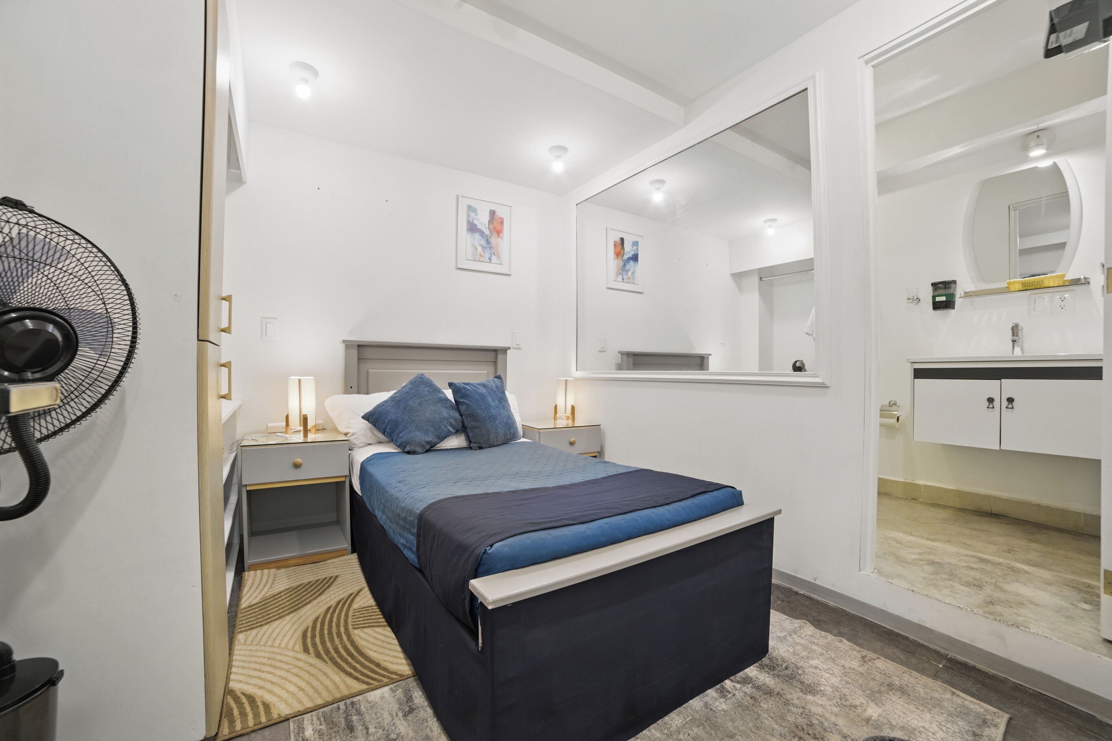 Una camera da letto moderna con un letto, comodini, uno specchio e una ventola.