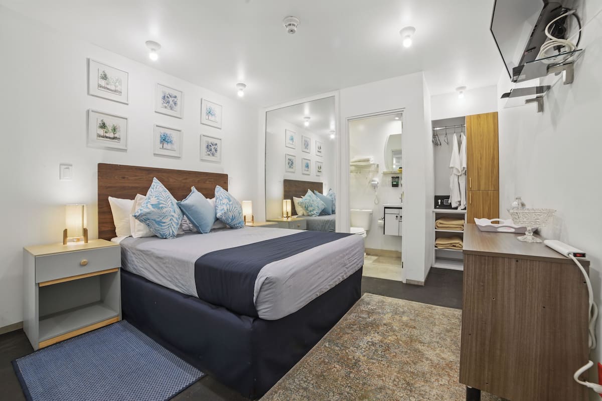 A modern bedroom with a large bed, bedside tables, a dresser, and a mirror.