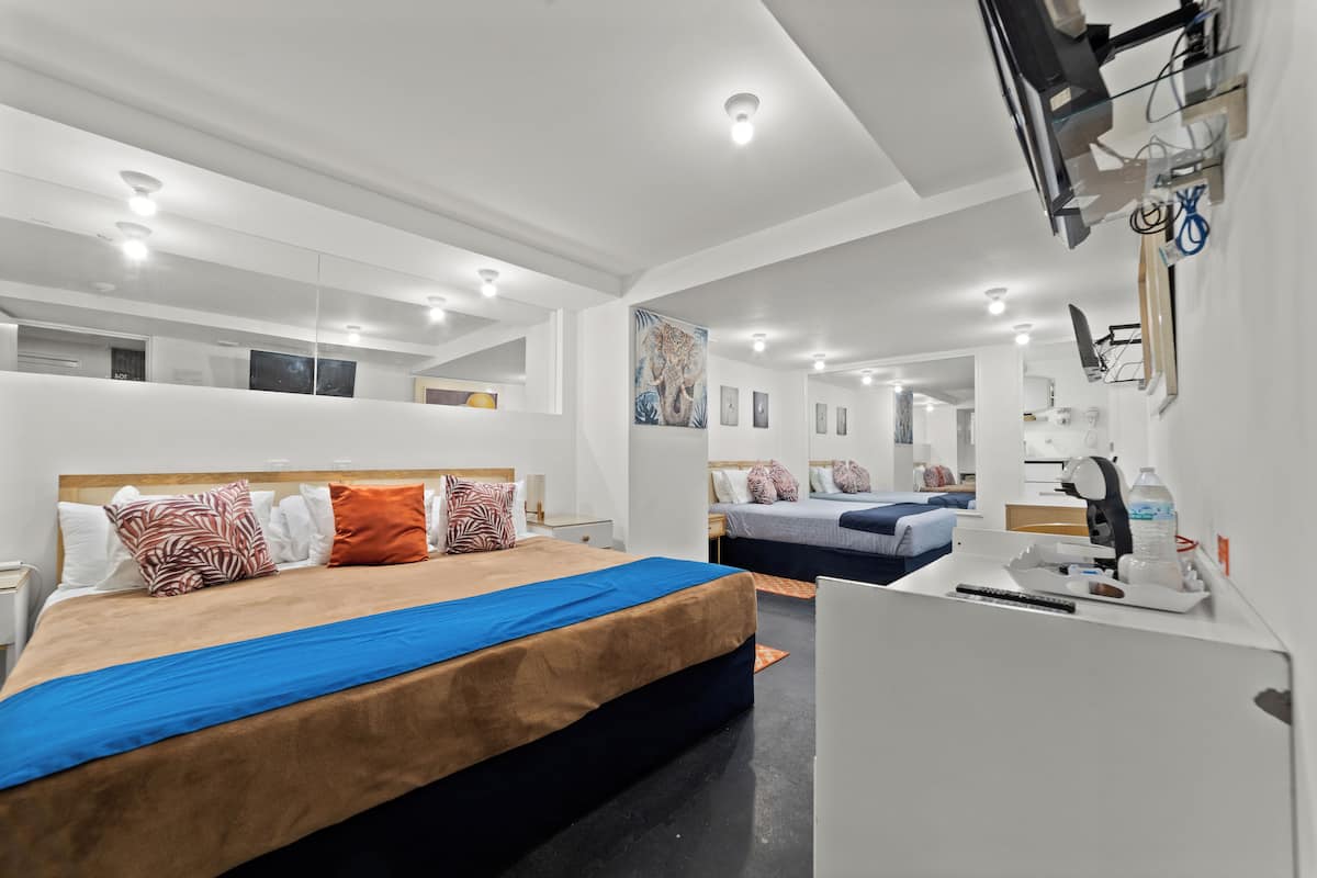 A modern hotel room with a large bed, a desk, and a mirror.
