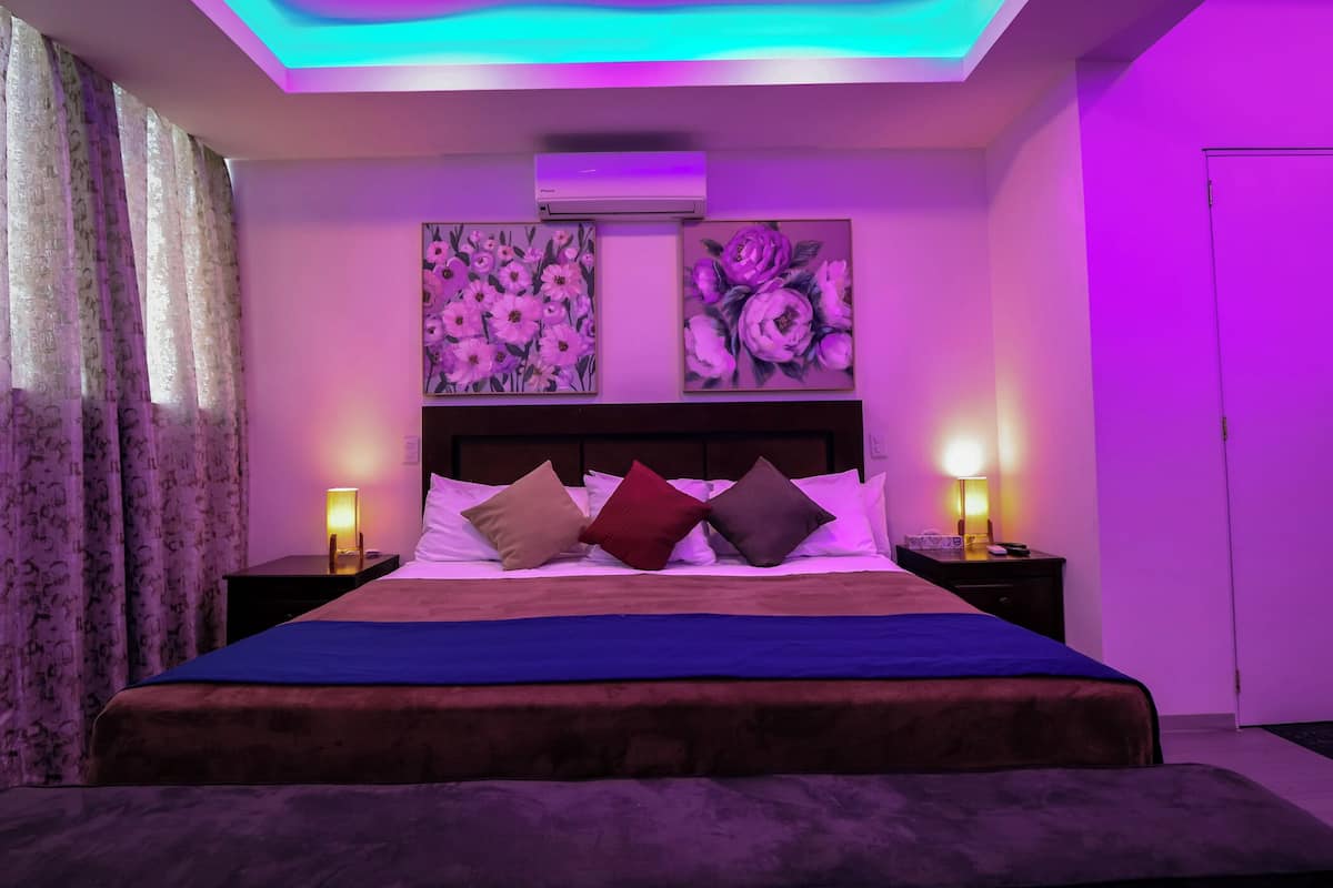 A bedroom with a bed, two bedside tables, and wall-mounted air conditioning.