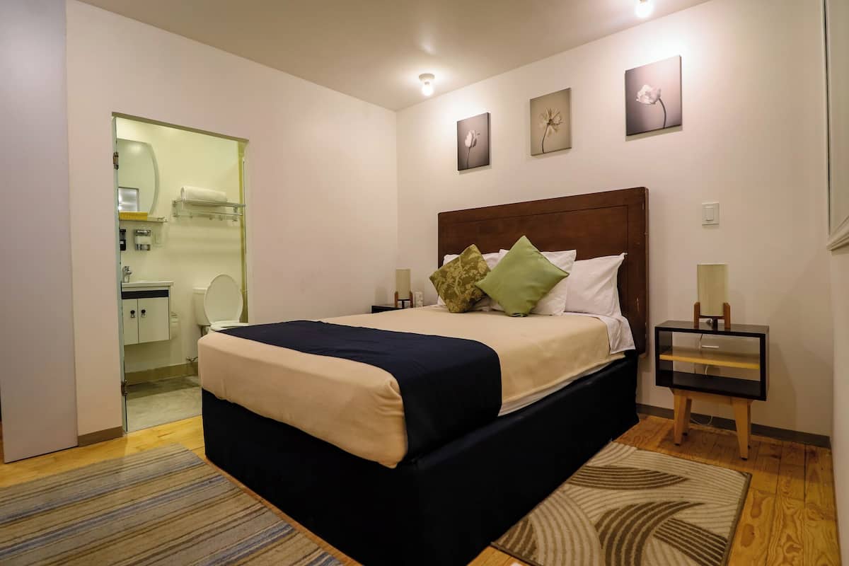 A neatly arranged bedroom with a bed, bedside tables, and a small bedside table with a lamp.