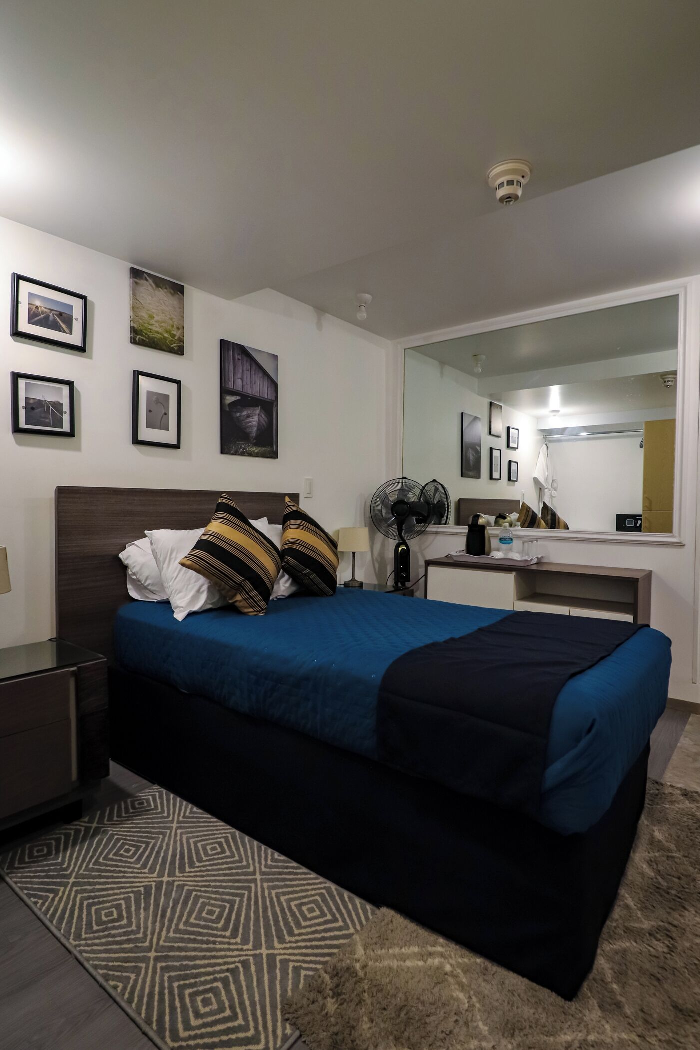 Une chambre bien rangée, avec un lit, une table de chevet et un miroir.
