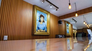 A reception area with wooden paneling, framed portraits on the wall, and a reflective floor. - Hotel Boutique Emma  (Mexico City)