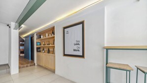 A modern interior with a kitchen area, a framed motivational quote on the wall, and a bar stool. - Hotel Boutique Emma  (Mexico City)