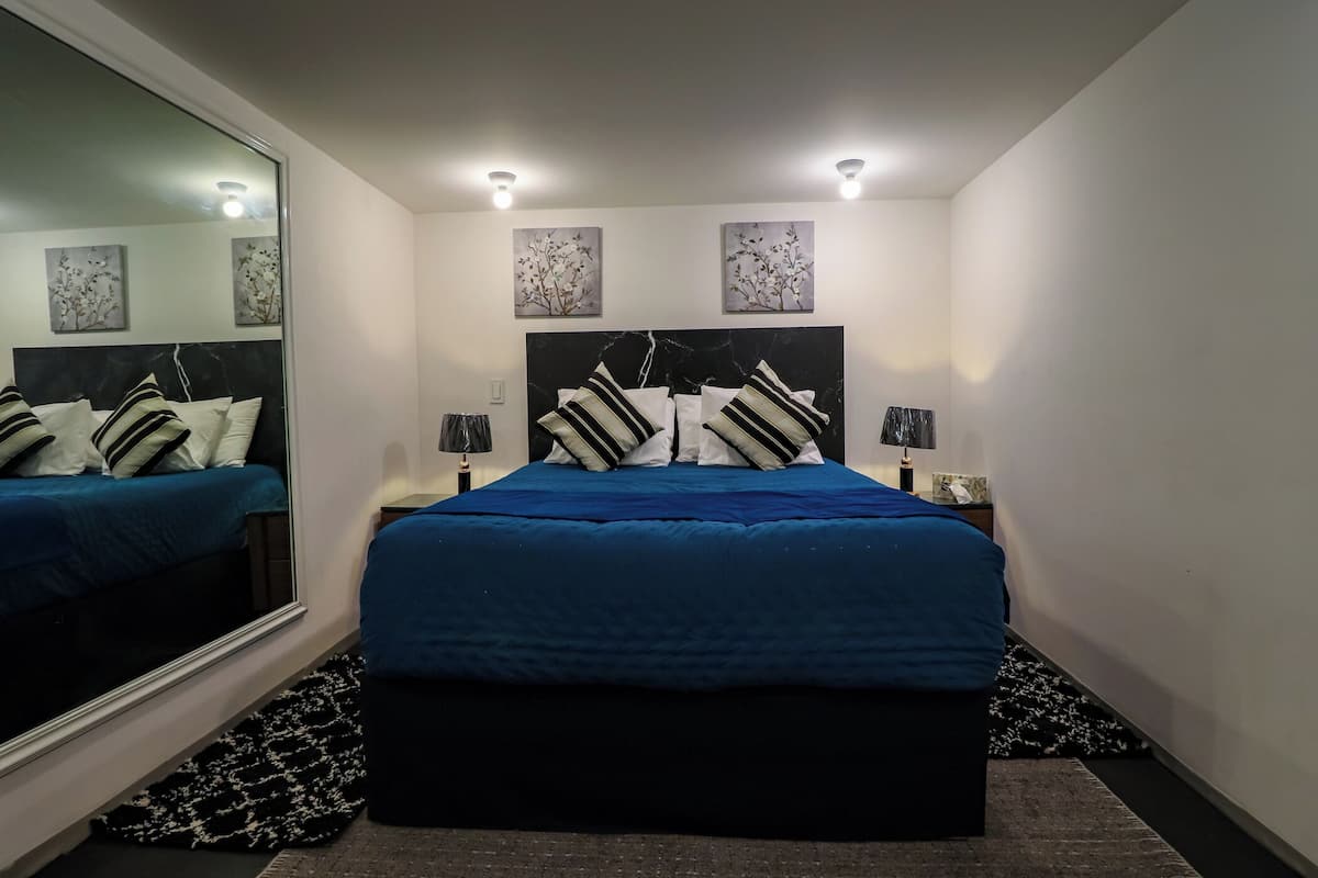 A bedroom with a large bed, two bedside tables, and wall-mounted artwork.